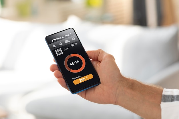 Free photo man holding a smartphone with a home automation app