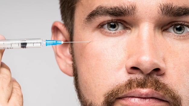 Man holding a syringe on his face