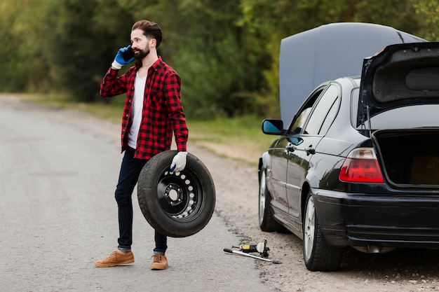 Free Photo man holding tire and talking on phone