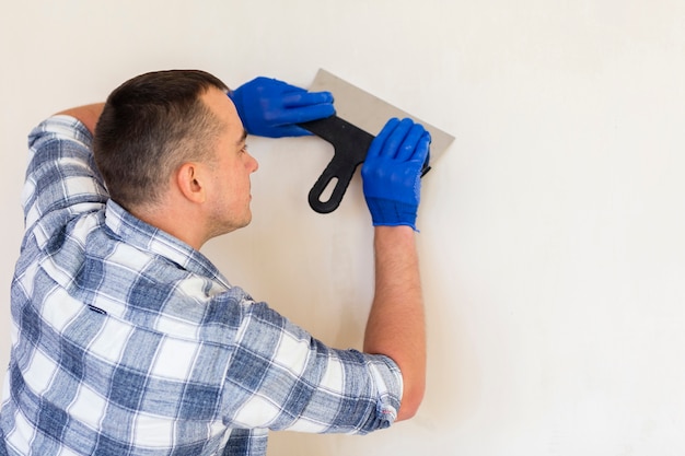 Man holding a trowel while working on wall