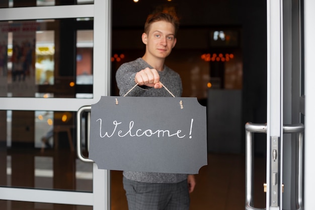 Free photo man holding welcome sign front view