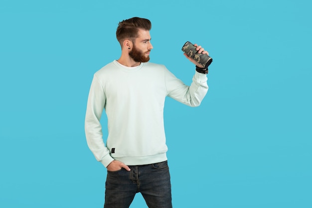  man holding wireless speaker listening to music isolated on blue