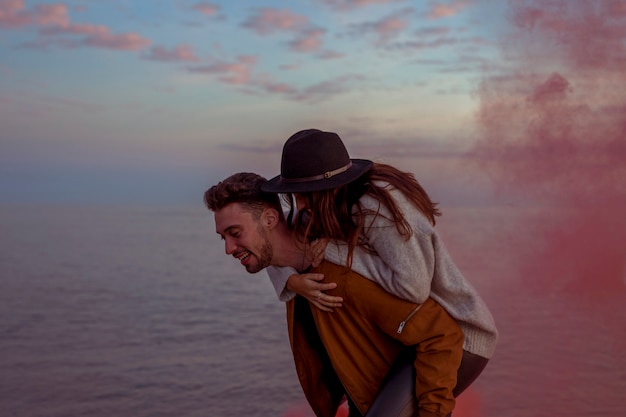 Man holding woman on back on sea shore 