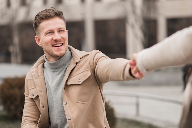 Free Photo man holding woman's hand outdoors