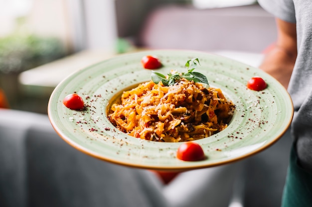 Free Photo man holds fettuccine pasta chicken mushroom parmesan tomato mint sumakh side view