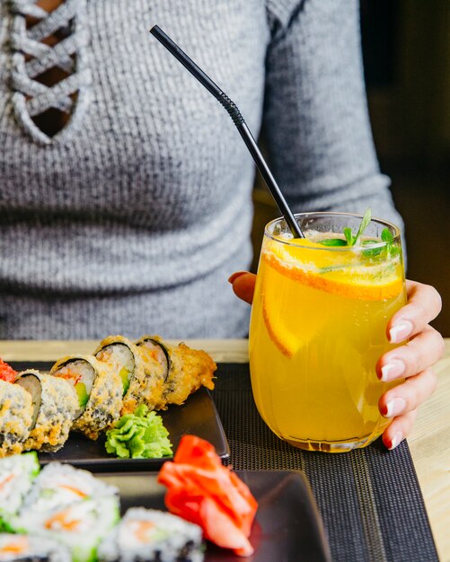 Man holds glass with citrus cocktail orange mint sparkling water side view