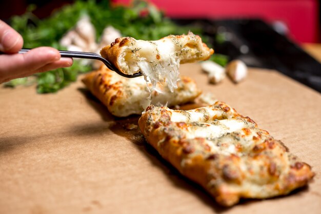 Man holds a piece of turkish pastry stuffed with cheese