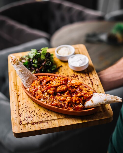 Man holds seafood fajitas prawns vegetables cheese lavash green salad sour cream side view