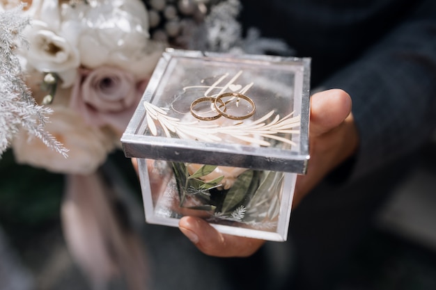 Man holds a small clear box with two wedding rings