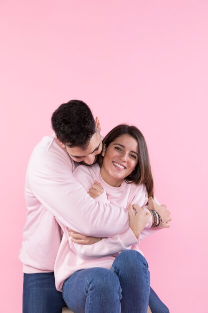 Man hugging cheerful young woman on stool