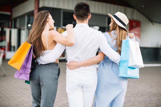 Free photo man hugging two women going shopping