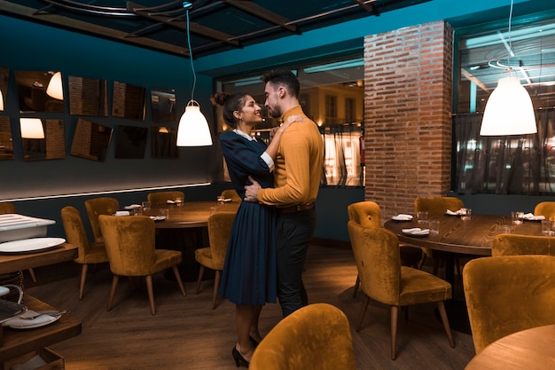 Man hugging with cheerful woman in restaurant