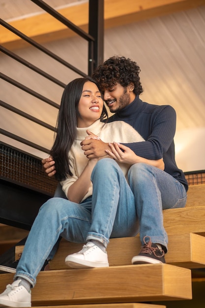 Man hugging woman sitting on stairs