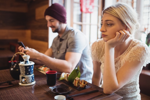 Man ignoring woman while using mobile phone