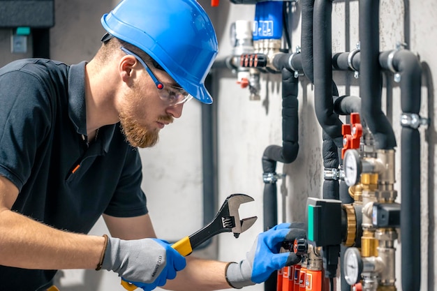 A man installs a heating system in a house and checks the pipes with a wrench