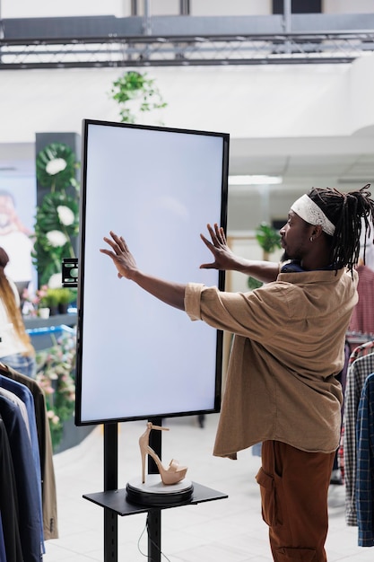 Free Photo man interacting with digital screen offering shoes to customer