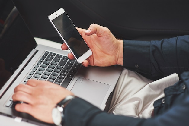 Man is a man working on a laptop and testing on mobile devices.