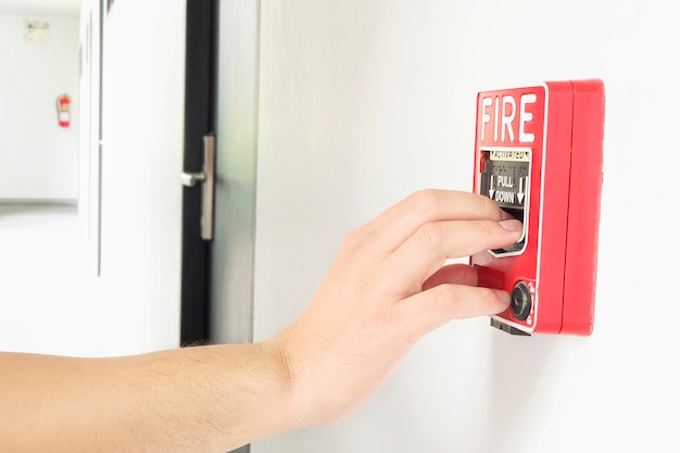 Man is reaching his hand to push fire alarm hand station