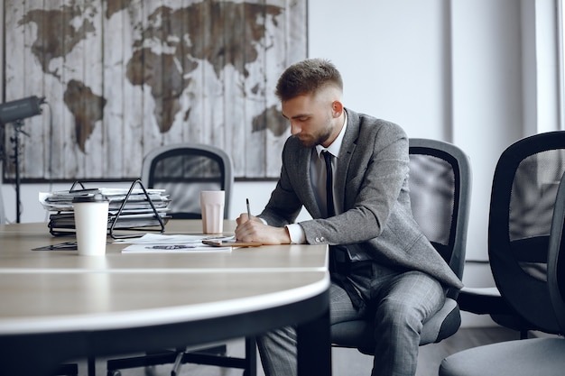 Free photo man is sitting at the table. guy in a business suit. businessman  signs thedocuments