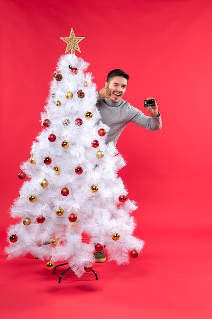 A man is standing next to the Christmas tree