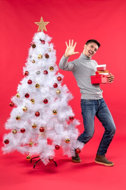 A man is standing next to the Christmas tree