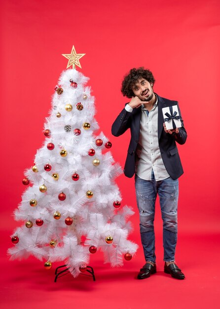 A man is standing next to the Christmas tree