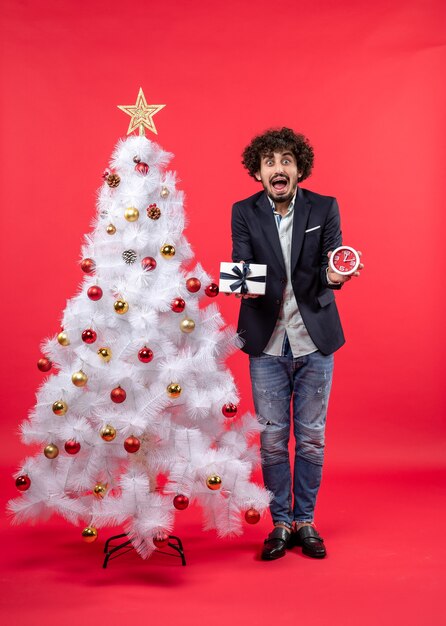 A man is standing next to the Christmas tree