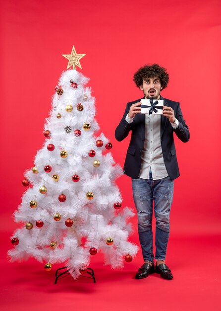 A man is standing next to the Christmas tree