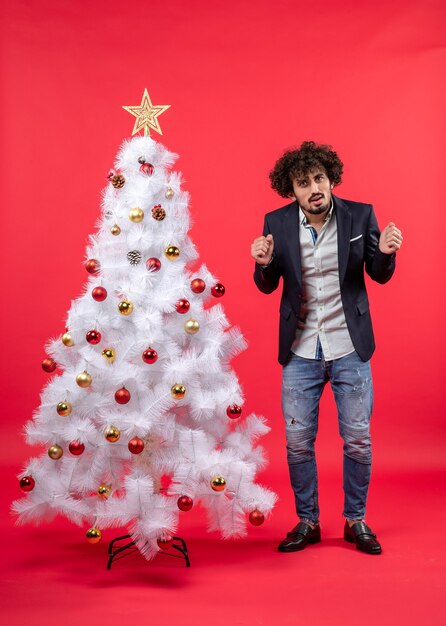 A man is standing next to the Christmas tree