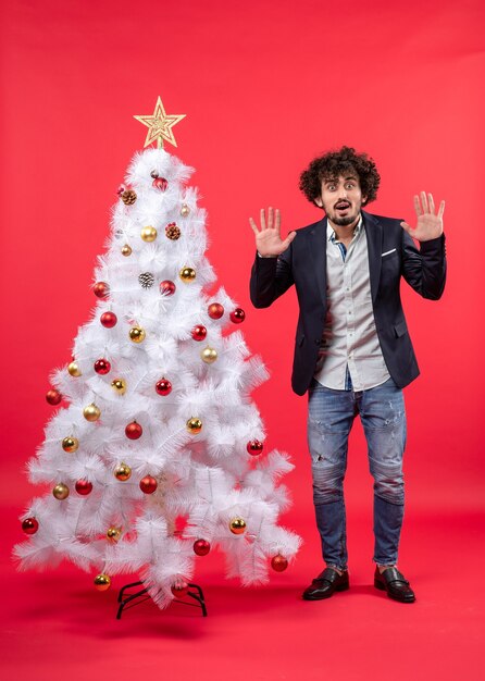 A man is standing next to the Christmas tree