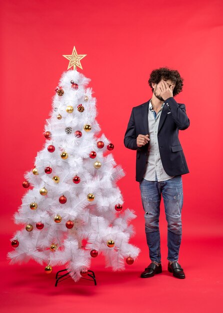 A man is standing next to the Christmas tree