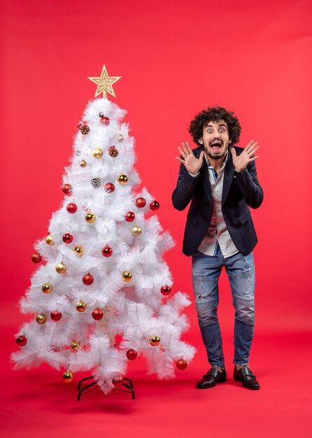 A man is standing next to the Christmas tree