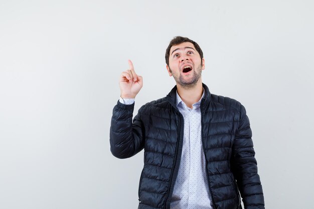 The man is suprising by poinitng up with his forefinger on white background