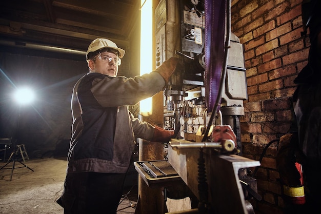 Free photo man is working with giant drill at busy metal factory.