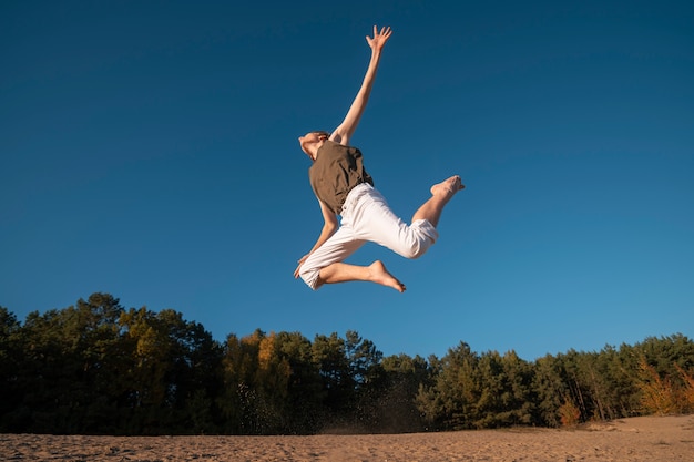 Free Photo man jumping in nature low angle