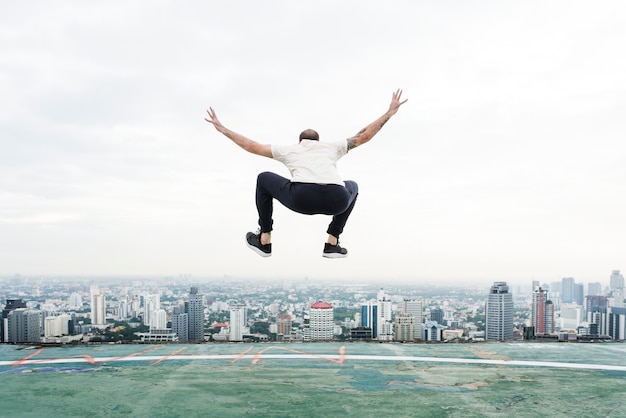 Free photo man jumping on the rooftop