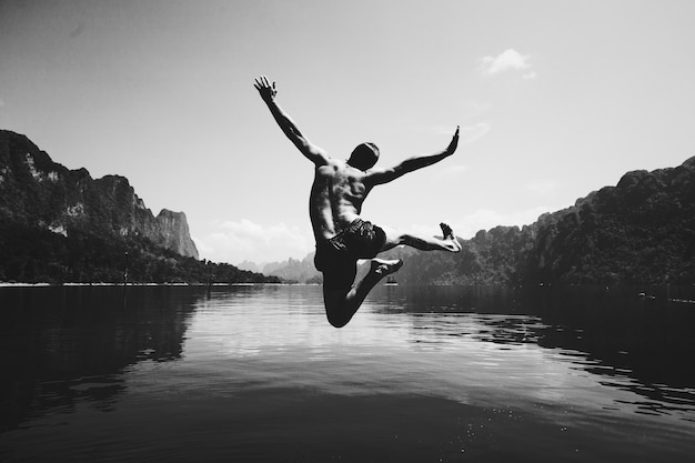 Free photo man jumping with joy by a lake