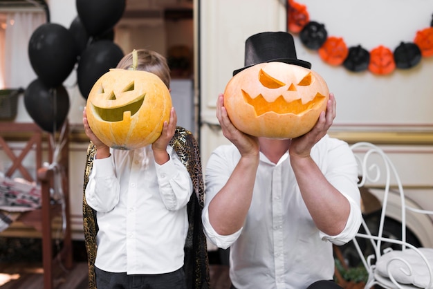 Man and kid holding carved pumpkins