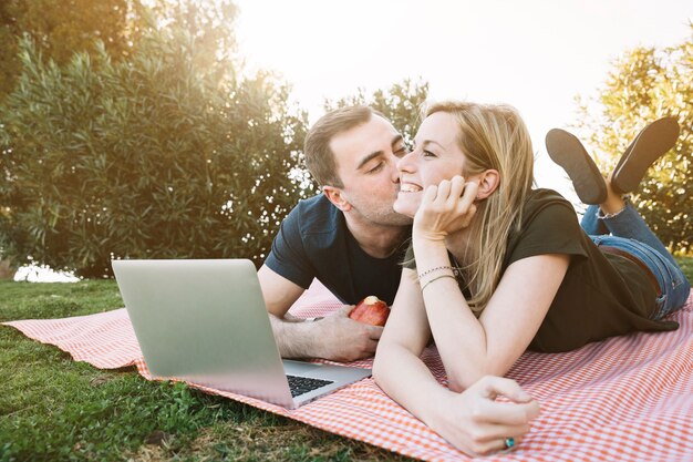 Man kissing cheerful woman on picnic