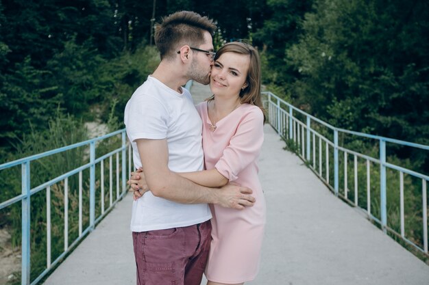 Man kissing in the face his girl on a bridge