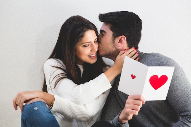 Man kissing a girl in the face and this one reads a postcard