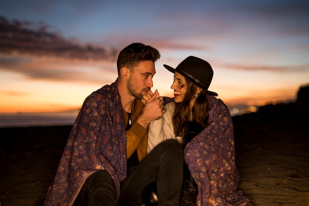 Free photo man kissing hand of woman on sitting on sea shore