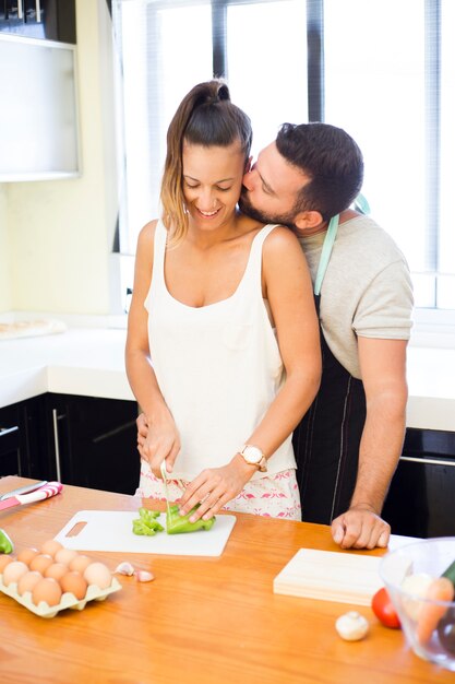 Man kissing his wife while preparing food in kitchen