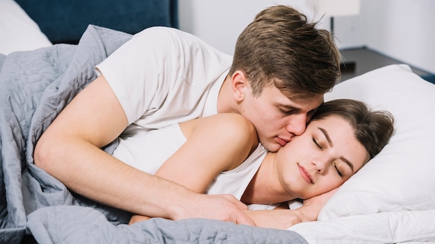 Man kissing sleeping woman on cheek 