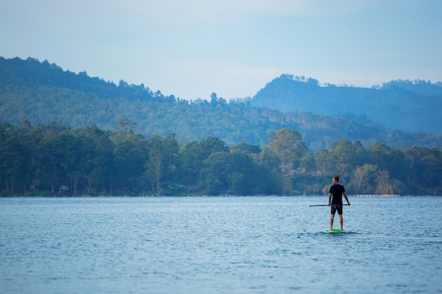 A man on the lake ride a sup board.