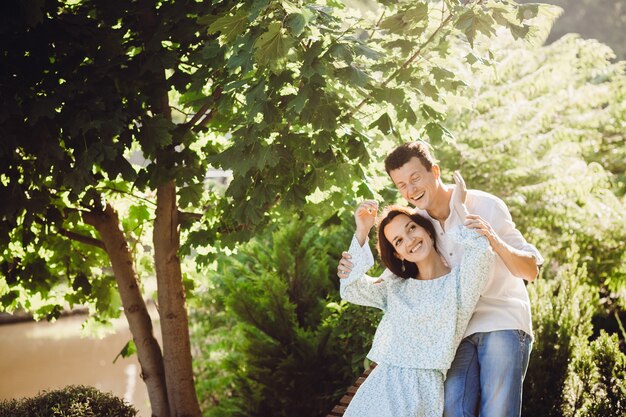 Man laughs sitting with his lady on wooden bench outside 