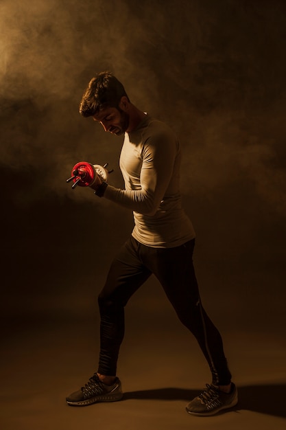 Free Photo man lifting dumbbells in dark room