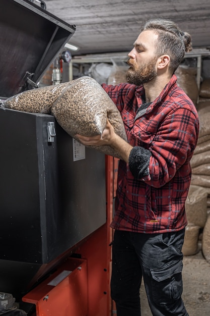 The man loads the pellets in the solid fuel boiler, working with biofuels, economical heating.