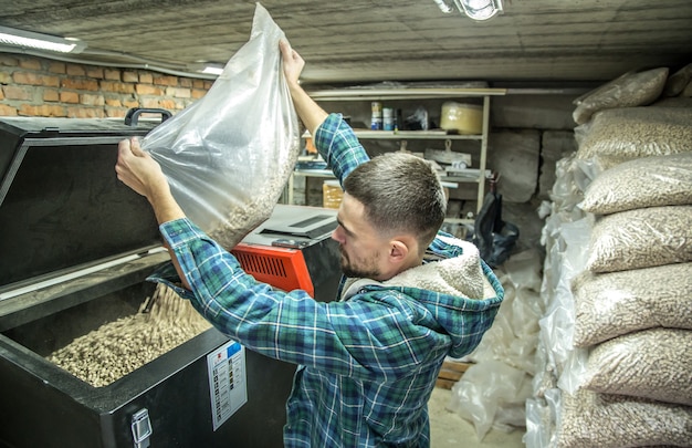 the man loads the pellets in the solid fuel boiler, working with biofuels, economical heating