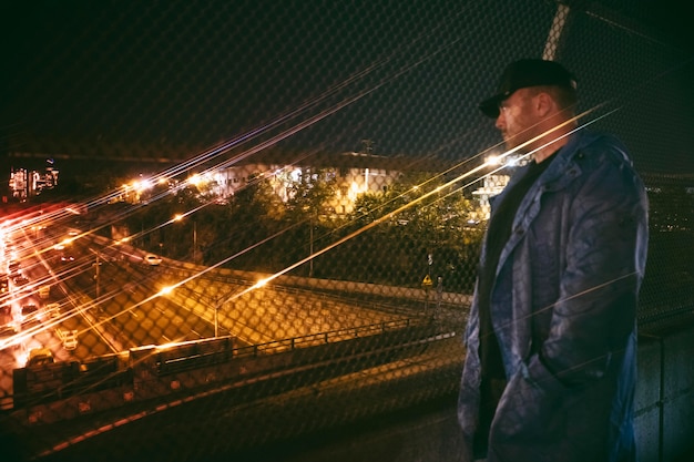 Man looking at busy city highway at night on the bridge